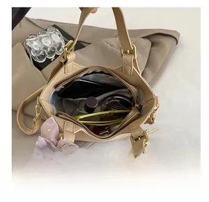 Détail montrant l'intérieur spacieux du sac à main beige avec des objets du quotidien