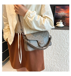 Detail of taupe crossbody saddle bag with woven texture and C-shaped metal clasp buckle