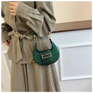 Borsa a mezzaluna verde scuro con motivo a coccodrillo e fibbia dorata indossata da una modella