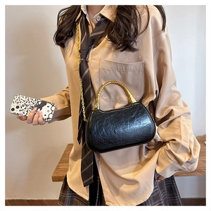 Close-up of black glossy textured leather box bag with iconic golden bamboo handle
