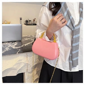 Detail of pink semi-circular box bag with golden bamboo handle and chain strap