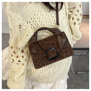 Close-up of leopard print crossbody bag with black square buckle and knotted top handle