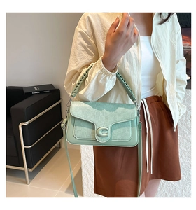 Detail of mint green quilted saddle bag featuring a signature C-shaped metal buckle clasp