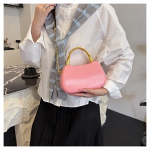 Detail of pink glossy handbag featuring a gold bamboo handle and metallic chain strap