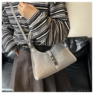 Detail of grey leopard print handbag with silver clasp on woman wearing striped shirt