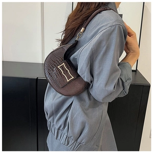 Dettaglio della borsa a mezzaluna marrone scuro con fibbia dorata e texture a coccodrillo