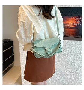 Close-up of mint green handbag with quilted texture and metallic C-shaped buckle