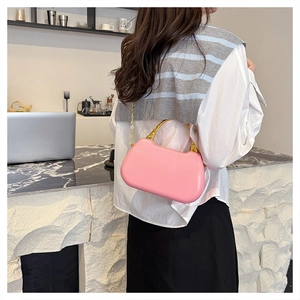 Pink glossy box bag detail with gold bamboo handle and chain strap on a white shirt