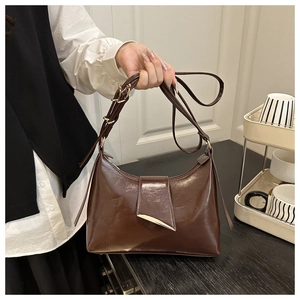 Detail of dark brown glossy underarm bag with triangular flap and golden metal buckle