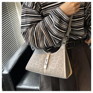 Detail of grey leopard print bucket bag with silver metal buckle on a shoulder strap