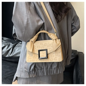 Detail view of beige leopard print crossbody bag with black square buckle and shoulder strap
