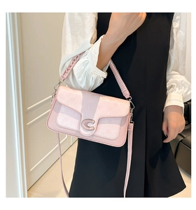 Detail of pink quilted handbag featuring a large gold C-shaped buckle and textured strap