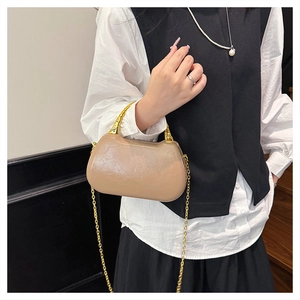 Detail of a brown pleated leather box bag with a golden bamboo handle and chain strap