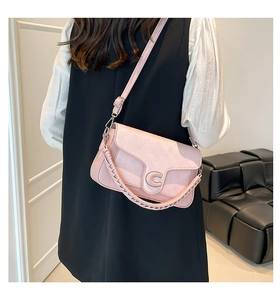 Detail of pink quilted crossbody bag with metal C-logo and woven handle on sofa