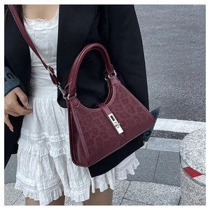 Detail of burgundy leather handbag with leopard print side panels and silver lock