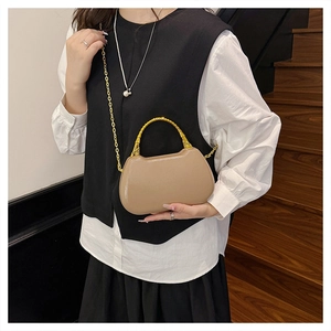 Detail of elegant beige box bag with gold bamboo handle and chain strap on model