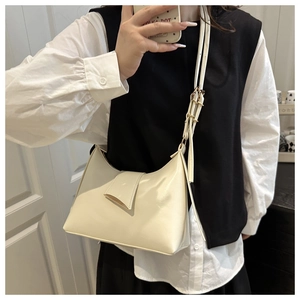 Detail of cream hobo shoulder bag with golden buckle on adjustable strap in daily use