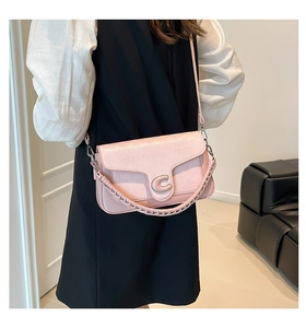 Close-up of pink checkered saddle bag featuring a C-shaped silver metal buckle and strap
