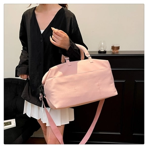 Pink waterproof travel duffel bag with shoulder strap shown on model in modern interior