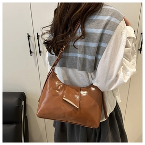 Brown hobo bag with gold metal clasp shown on shoulder with striped casual outfit