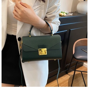 Dettaglio borsa in pelle opaca verde scuro con chiusura a T dorata e patta trapuntata