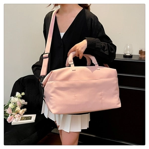 Pink travel bag with thick handles and adjustable shoulder strap shown on a model