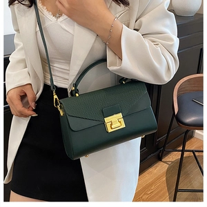 Dettaglio della borsa a scatola verde scuro con patta strutturata e chiusura dorata fine