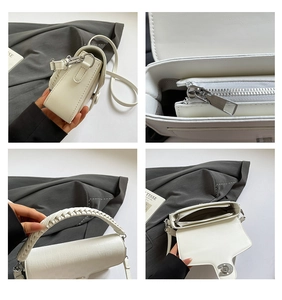 Detail view of white plaid saddle bag with woven handle and internal zipper pocket