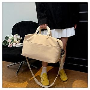 Close-up of beige travel duffel bag with reinforced handles and detachable shoulder strap