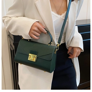 Dettaglio della borsa verde scuro con chiusura dorata e texture goffrata elegante