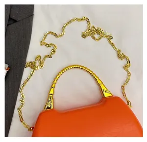 Detail of orange litchi grain leather bag with golden bamboo handle and chain strap