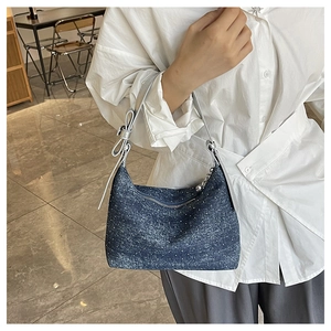 Detail of denim underarm bag with white polka dots and silver bow on the shoulder strap