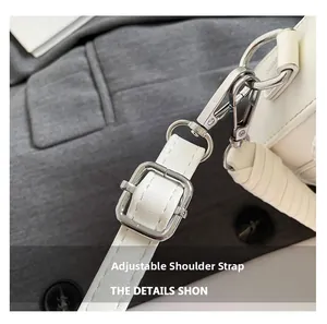 Detail of white bag featuring adjustable faux leather strap and silver metal hardware buckle