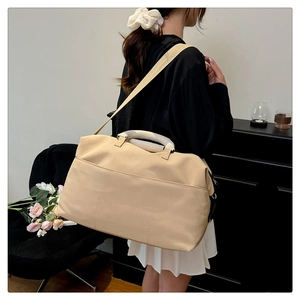 Detail of beige large travel bag worn by model showing size and adjustable shoulder strap