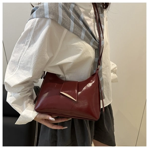 Burgundy patent leather tote bag with gold buckle styled on model with white shirt