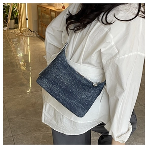 Detail of dark blue denim crossbody bag with sequin dots worn by model in home setting