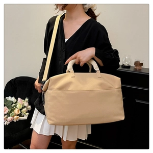 Close-up of adjustable strap and spacious front pocket on a beige travel duffel bag