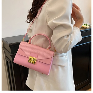 Dettaglio borsa a mano rosa con patta intrecciata e chiusura in metallo dorato lucido