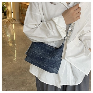 Detailed texture of blue denim hobo bag featuring white polka dot rhinestones and silver strap