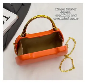Detail view of the orange box bag interior with gold bamboo-style handle and chain strap