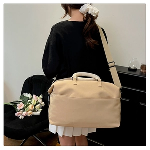 Detail of beige travel bag showing wide front pocket and adjustable shoulder strap