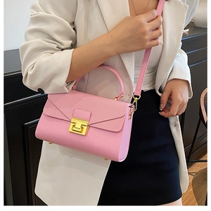 Dettaglio borsa a tracolla rosa con patta motivo serpente e chiusura dorata su blazer bianco