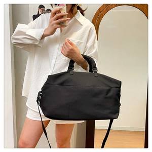 Mirror selfie showing the large capacity black nylon travel tote with shoulder strap
