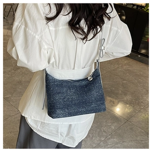 Detail of blue denim shoulder bag with silver polka dots and a heart zipper pull
