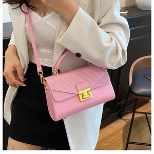 Dettaglio della borsa in pelle rosa con texture intrecciata e chiusura dorata su modella
