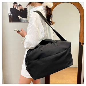 Lifestyle view of large black travel duffel bag with shoulder strap in a home setting