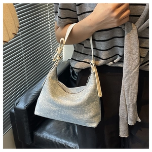 Close-up of hobo shoulder bag featuring light blue denim texture and silver rivet details
