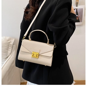 Dettaglio borsa beige con trama a V e chiusura dorata indossata con un blazer nero chic
