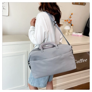 Close-up of durable light gray travel bag featuring thick handles and adjustable strap