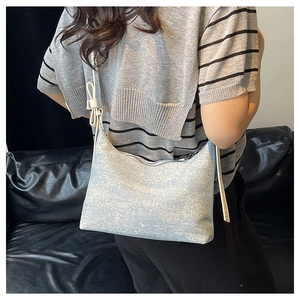 Model wearing a light blue denim hobo bag with white knotted shoulder strap